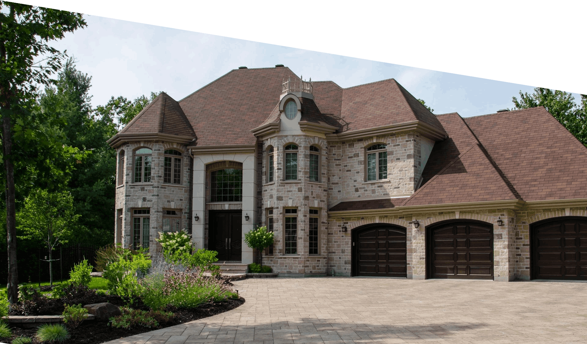 Front of large, multi-story home with 3 car garages and paved driveway and entryways.